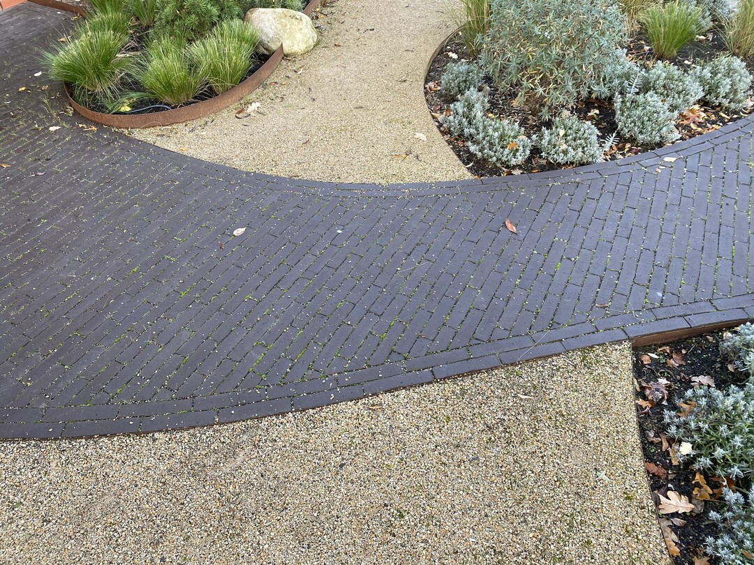   Viele Grser und Stauden sowie eine organisch geschwungene Pflasterung aus dunklen Pflasterklinkern, die durch eine Decke aus wassergebundener Decke fhren, machen den Sylt-Garten aus.
