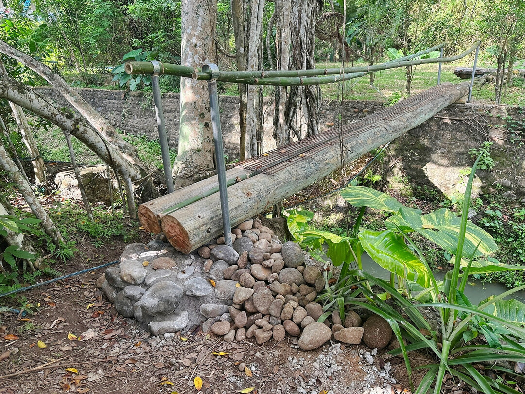 Nun verkürzt die Brücke den Weg zu den Fischteichen und den Anbauflächen auf der anderen Seite des Bachs. Ein Gitter aus Armiereisen hält sie auch bei nassem Wetter passierbar.