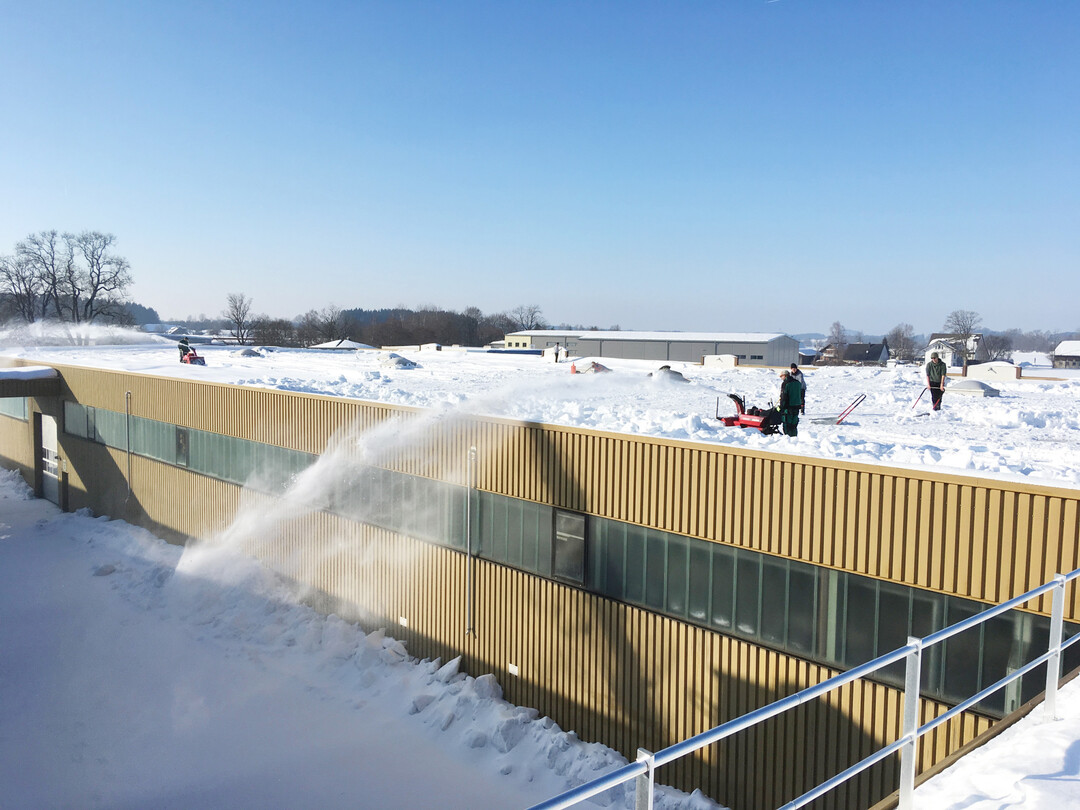 Der Schnee wird von der Mitte zum Rand und von da ber die Dachkante gefrst.