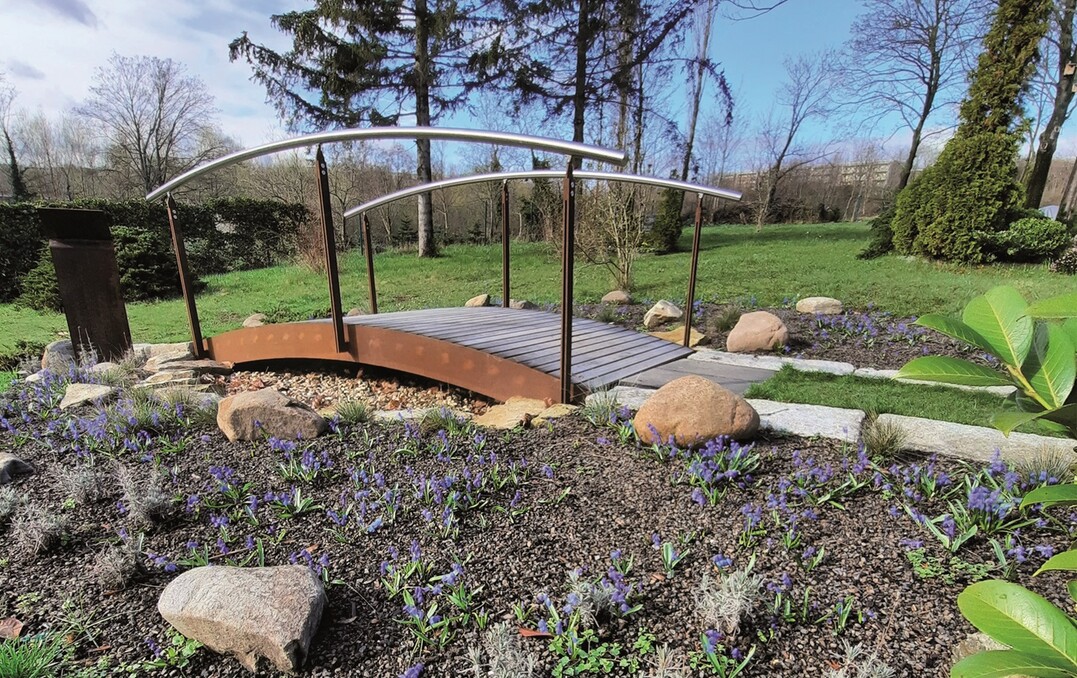 Die gebogene Brücke aus Metall als Gestaltungselement und zur Strukturierung im
Garten