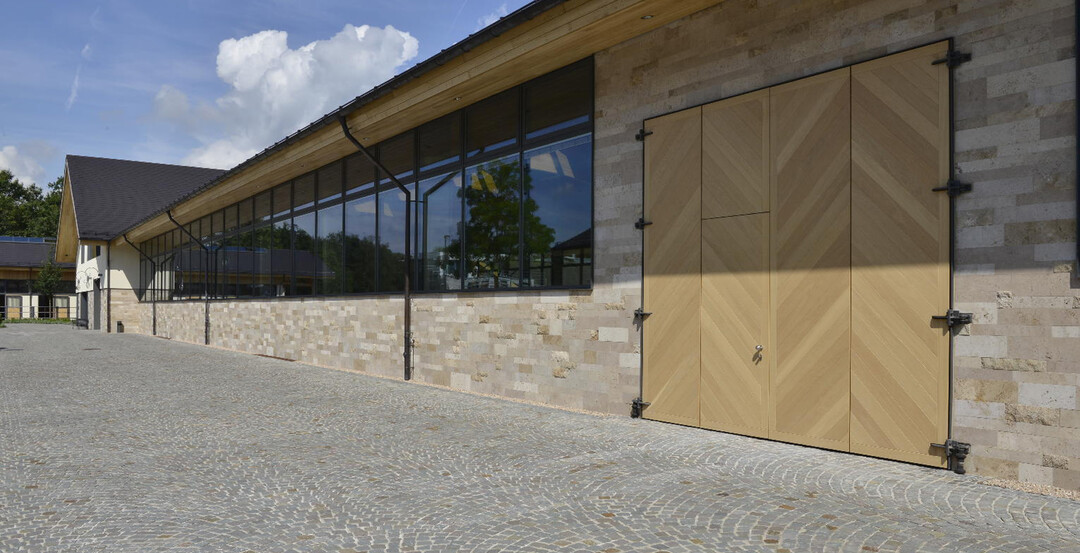 An der Auenfassade der Reithalle kam Thringer Travertin aus den Steinbrchen in Bad Langensalza und Weimar-Ehringsdorf zum Einsatz. Der porige Naturstein sorgt fr eine klassische und zeitlose Optik.