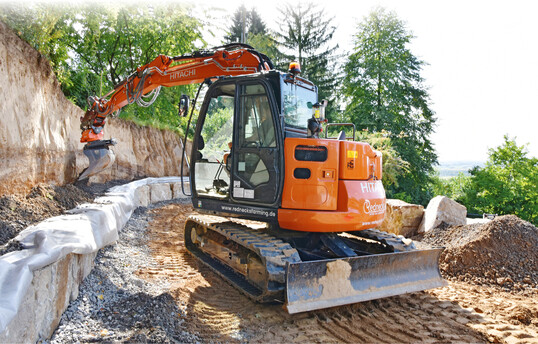   Randnah Mineralgemisch anschtten hinter der nchsten Steinlage  das Setzen von Natursteinmauern klappt mit Bagger und Tiltrotator wie aus dem Handgelenk.  