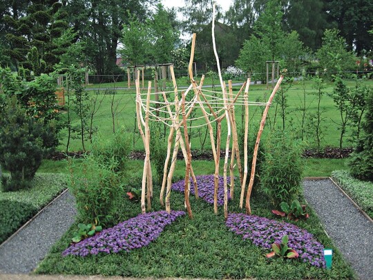 Grabgestaltung mit Ophiopogon als Bodendecker, Fargesia und Bergenia im Rahmen zum experimentellen Grabzeichen aus unterschiedlichen Edelhlzern