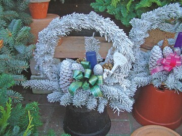 Ein Gesteck aus Tanne mit Zapfen und Kerze als Grabschmuck