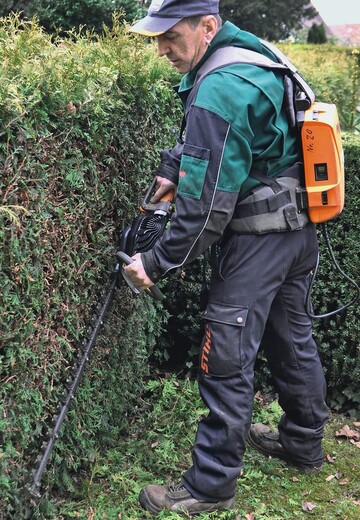 Friedhofsgrtner Dieter Wenz erledigt den jhrlichen Formschnitt an seinen Hecken auf dem Ettlinger Stadtfriedhof mit einer Akkumaschine. Ihre rckengetragene Akkueinheit liefert genug Energie fr einen ganzen Arbeitstag