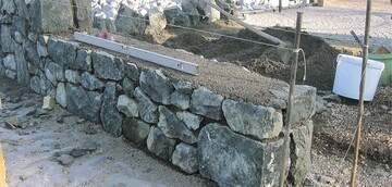 Doppelhuptige Zyklopenmauer mit Monokornbeton als Mauerkern, in der Bauphase.
