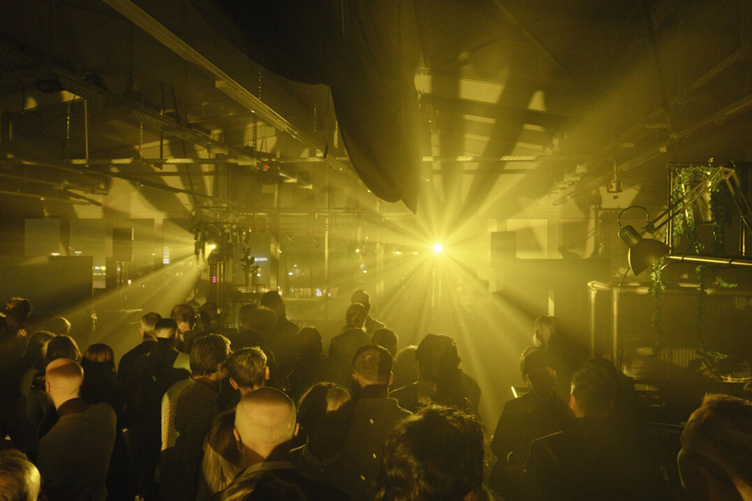 Große Gruppe von Gästen verfolgt aufmerksam die Lichtershow auf der Bühne.