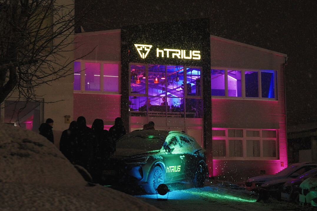 Beleuchtetes hTRIUS-Firmengebäude von außen.