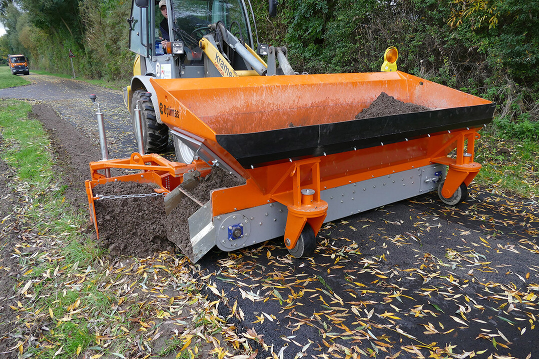 Die Optimas Finliner Materialverteilschaufel in der 1,4 m³ Variante bei der Bankettreparatur